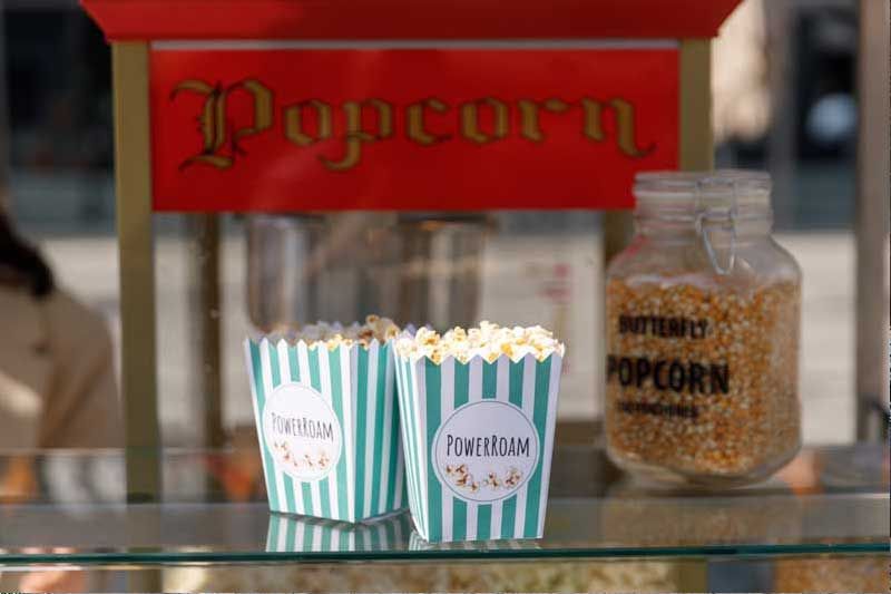 Popcornbecher mit Branding bei einer Veranstaltung, präsentiert vor einer Popcornmaschine.