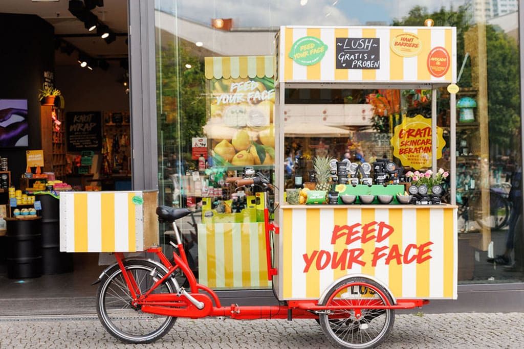Mobiler Kosmetikstand mit gelb-weißem Design vor einem Berliner Geschäft