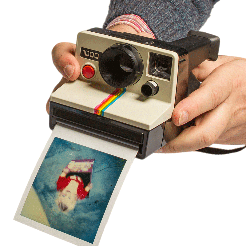 Ein Mann hält eine klassische Fujifilm Polaroid-Sofortbildkamera, aus der gerade ein Foto ausgedruckt wird. Die Kamera, erkennbar an ihrem ikonischen Regenbogenstreifen, ist in Cremeweiß und Schwarz gehalten und produziert ein Bild, das gerade von den Händen des Nutzers entgegengenommen wird.