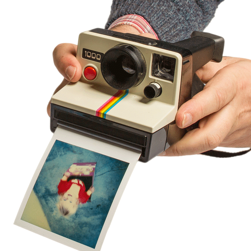 Ein Mann hält eine klassische Fujifilm Polaroid-Sofortbildkamera, aus der gerade ein Foto ausgedruckt wird. Die Kamera, erkennbar an ihrem ikonischen Regenbogenstreifen, ist in Cremeweiß und Schwarz gehalten und produziert ein Bild, das gerade von den Händen des Nutzers entgegengenommen wird.