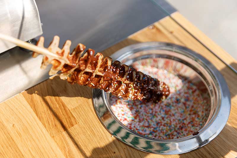 Vegane Waffel wird bei einer Promotion in Berlin in bunte Streusel getaucht.