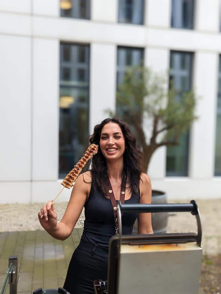 Fröhliche Mitarbeiterin serviert Waffeln bei einer LinkedIn Promotion mit einem gebrandeten Waffelwagen.