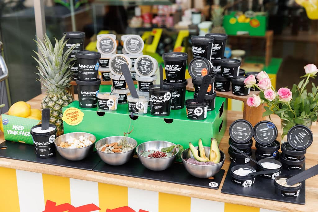 Kosmetikprodukte mit Dekoration aus Avocado, Minze und Blüten in Nahaufnahme