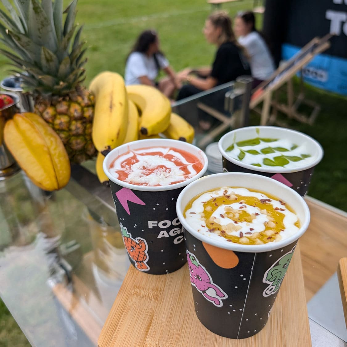 Smoothie Bike Becher Branding mit individuell gestalteten Smoothie-Bechern und frischen Früchten auf einem Event.