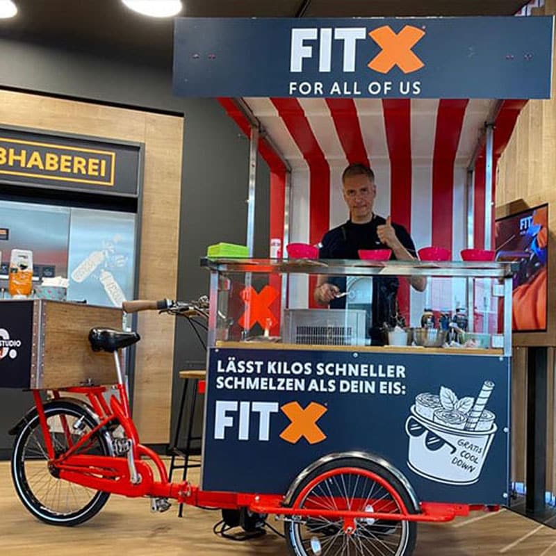 Eisfahrrad mieten mit gebrandeter Kugel-Eis-Station auf einer FITX-Messeveranstaltung.