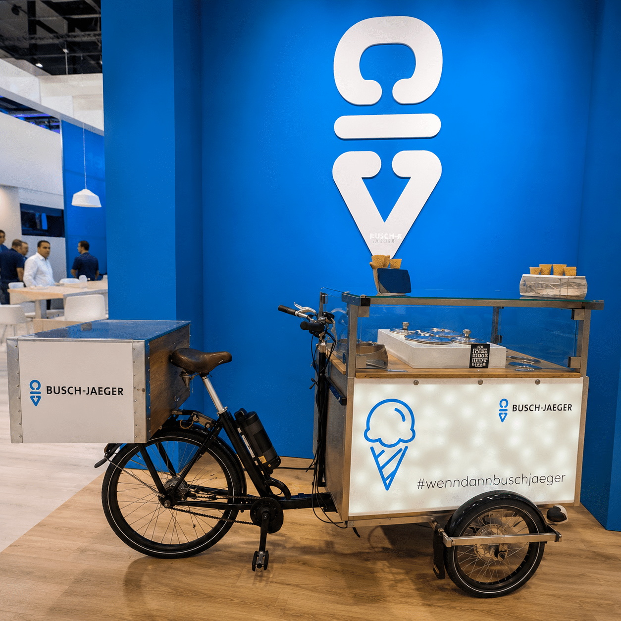 Eisfahrrad mieten mit gebrandeter Kugel-Eis-Station auf einem modernen Messestand.