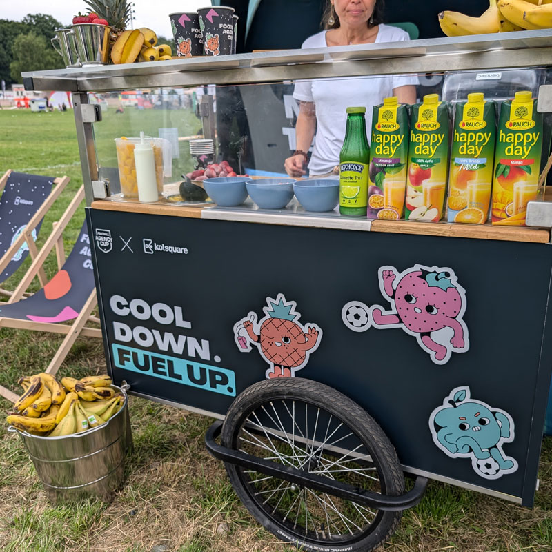 Smoothie Bike Promotion mit gebrandeter Smoothie-Station, frischen Früchten und Säften auf einer Outdoor-Veranstaltung.